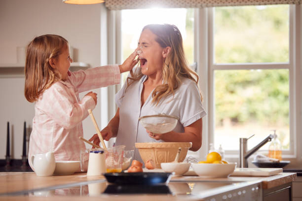 mutter und tochter machen messy pfannkuchen in der küche zu hause zusammen - shrove tuesday stock-fotos und bilder