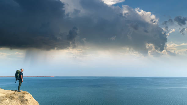istock The man with a backpack standing on a mountain on the sea background 1301006246