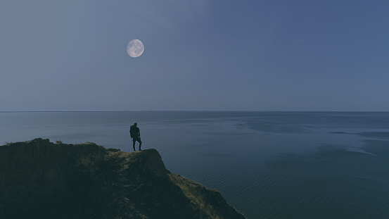 The hiker standing on the mountain against night sea view