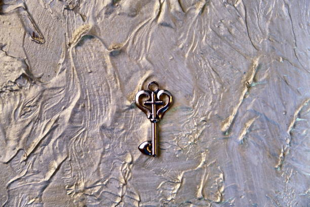 heart shaped vintage key on abstract  background coating putty with pearlescent paint rough wall surface with uneven coating with silver gold paint. retro noise grain effect