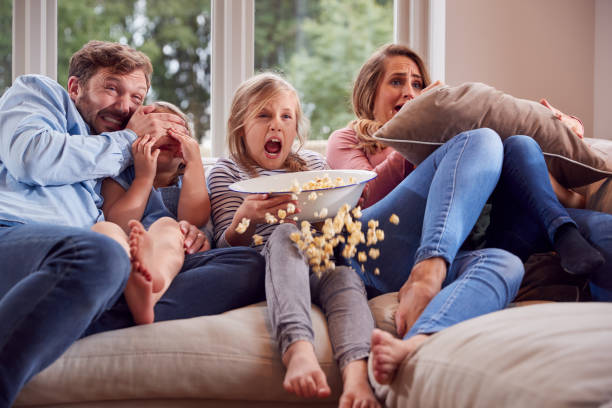 familia asustada sentada en el sofá en casa viendo la película de terror en la televisión con palomitas de maíz - sibling brother family with three children sister fotografías e imágenes de stock