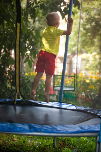 istock Happy child, active boy plays outdoors in playground jumping high on trampoline. 1301009471