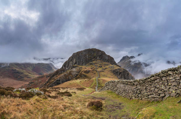 istock Epic Winter landscape image of view from Side Pike towards Langdale pikes with low level clouds on mountain tops and moody mist swirling around 1301012402