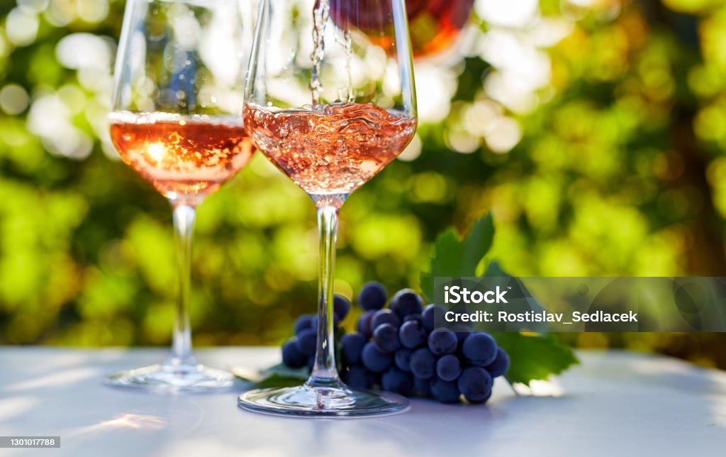 テーブルの上のグラスにバラワインを注ぐ - ロゼワインのロイヤリティフリーストックフォト
