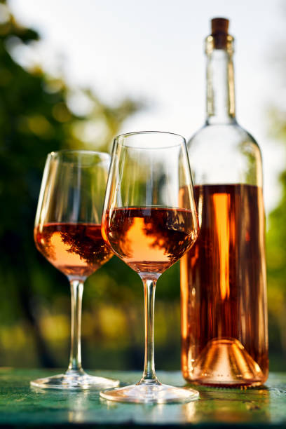 istock Two glasses of rose wine and a bottle on an old table 1301017800