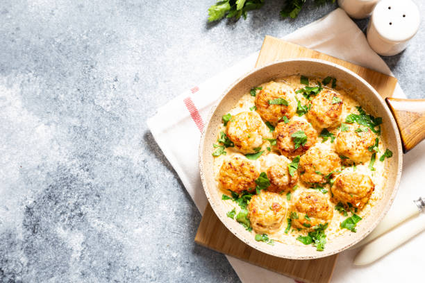 meatballs in white sauce in a frying pan on a gray background, comfortable homemade healthy food stock photo