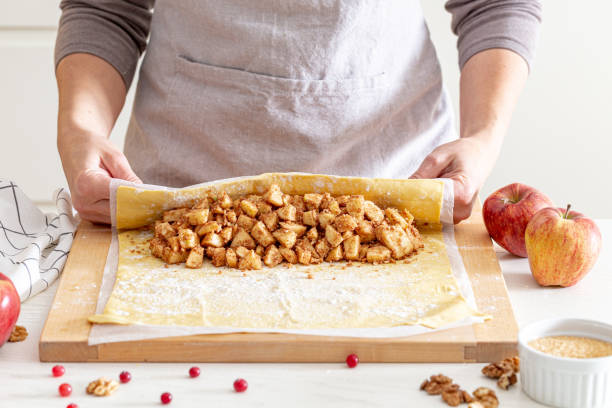 making strudel - dough, apples, cinnamon, nuts, brown sugar. woman preparing apple strudel making strudel - dough, apples, cinnamon, nuts, brown sugar. woman preparing apple strudel apple cinnamon pancake stock pictures, royalty-free photos & images