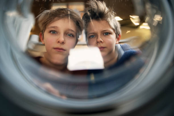 istock Two worried boys looking into washing machine and discovering laundry disaster 1301019286