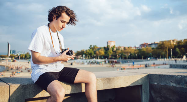 istock Caucasian tourist adjust settings on modern camera for photographing environment and practicing skills, young amateur man 20 years old with technology equipment editing pictures during free time 1301019366