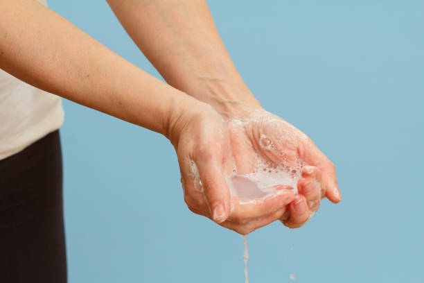 istock Woman washing hands with soap on blue background. 1301019520