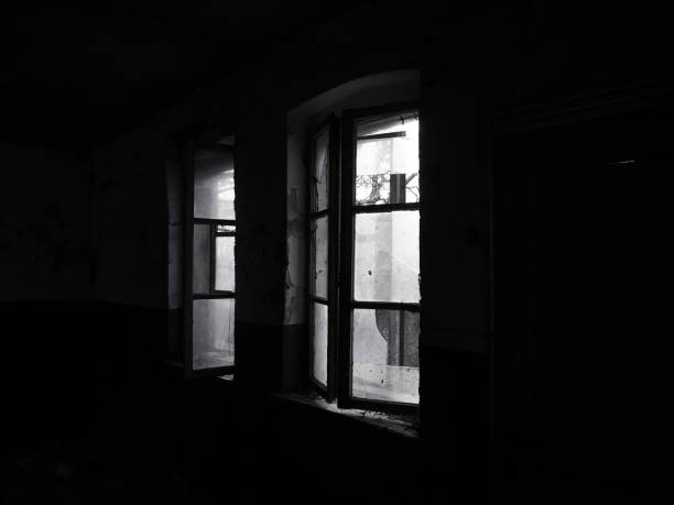 istock Scary windows. Inside an abandoned house. View of broken windows without a curtain. Grunge scene. Light shines through old wooden frames with broken glass. The concept of abandonment and uselessness 1301020043