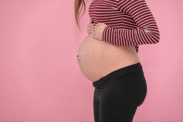 Side view of a pregnant woman's exposed belly