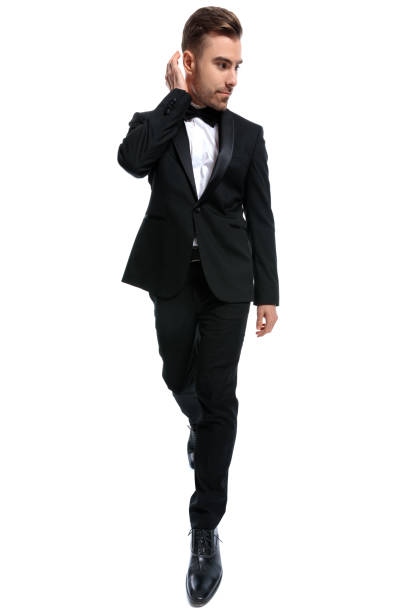 istock attractive young man in black tuxedo holding hand behind ear 1301026422