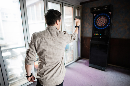 Successful young man playing darts, focusing on his aim