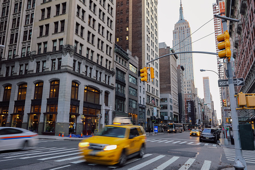 New York, USA - 04 05 2018: Fifth Avenue Manhattan morning traffic with yellow taxi cabs and cars. Fifth Avenue in New York City known for its luxury retail shops.