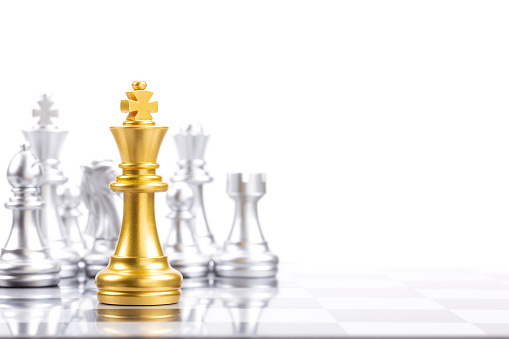 Gold king in battle chess game stand on chessboard against silver chess pieces on opposite side isoalted on white background, Leader and teamwork for business achievement strategy concept