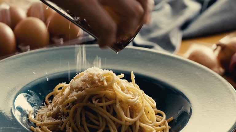 Grating parmesan cheese on pasta