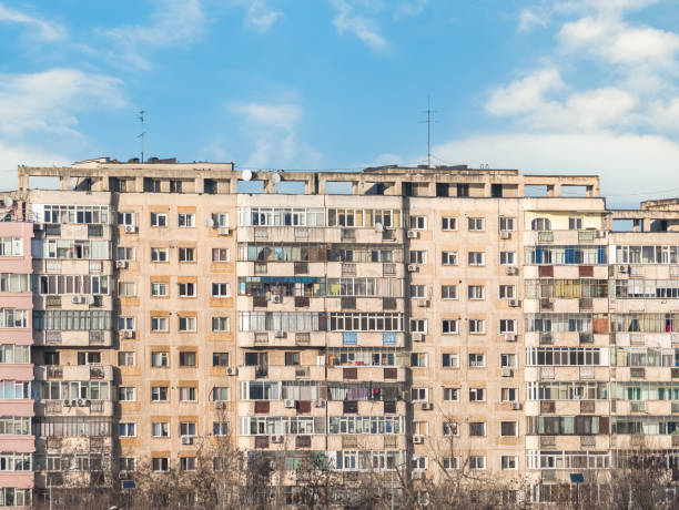 изношенный жилой дом коммунистической эпохи на фоне голубого неба в бухаресте румыния. гадкий традиционный комм�унистический жилищный анс� - прежний советский союз стоковые фото и изображения