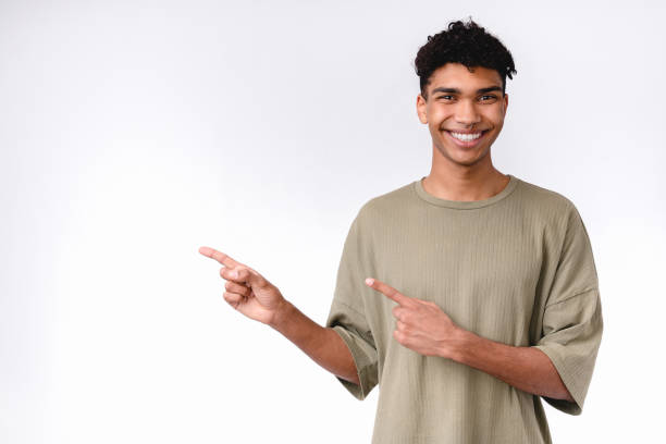 istock Smiling attractive afro-american man with nose piercing pointing at copy space isolated over white 1301037786