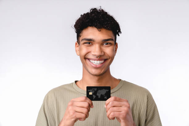 istock Smiling young african student showing credit card isolated over white background 1301038531