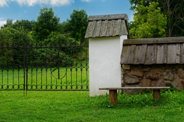 Fragment of the church fence with an iron gate against the background of the forest and sky