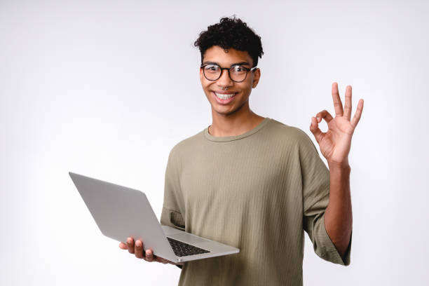 istock Happy young mixed-race student showing okay sign using laptop isolated over white background 1301038711