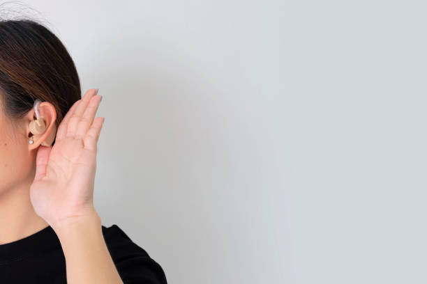 istock Listening concept. Young woman with hearing aid on light background 1301038821