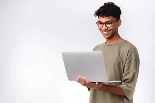 inteligente joven estudiante de raza mixta usando portátil aislado sobre fondo blanco - adulto joven fotografías e imágenes de stock