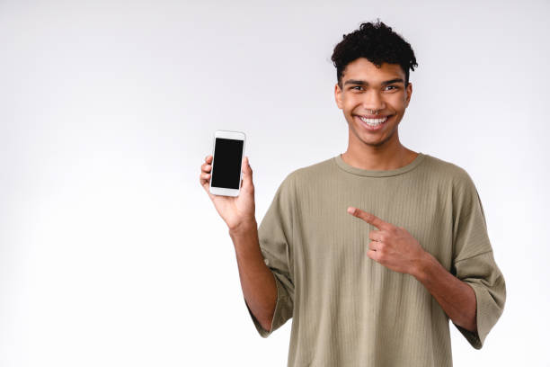 istock Confident young mixed-race man pointing at smart phone isolated over white background 1301039077