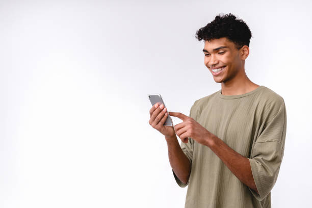 istock Cheerful young mixed-race man using smart phone isolated over white background 1301039202