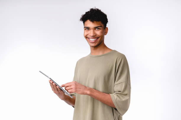 istock Smiling young african student using tablet isolated over white background 1301039860