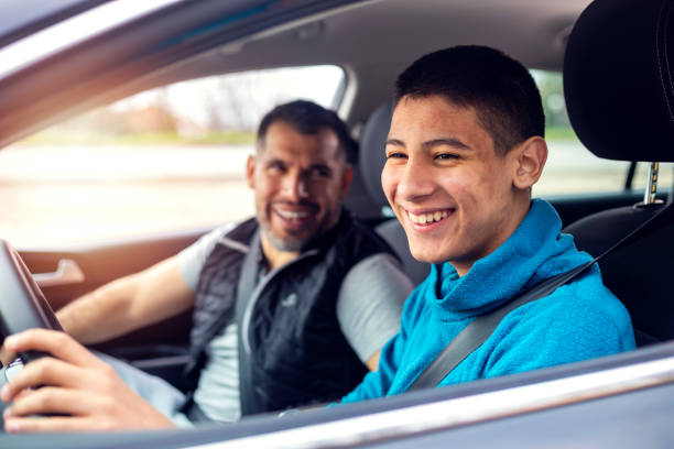 Teenage boy having driving lesson with male instructor A teenage boy sitting behind the steering wheel of a car and listening to his fathers instructions as he drives. car ownership photos stock pictures, royalty-free photos & images