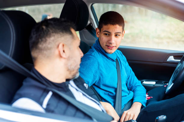 Teenage boy having driving lesson with male instructor A teenage boy sitting behind the steering wheel of a car and listening to his fathers instructions as he drives. teenager boy driving stock pictures, royalty-free photos & images