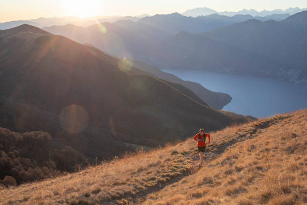 l’homme court au-dessus des montagnes et du lac au lever du soleil - locarno photos et images de collection