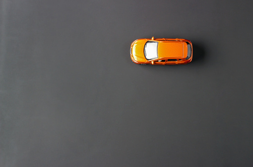 Orange toy car on a black background. View from above