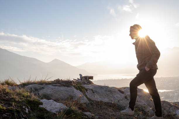 istock Young man walks up knoll above lake, sunset 1301041343