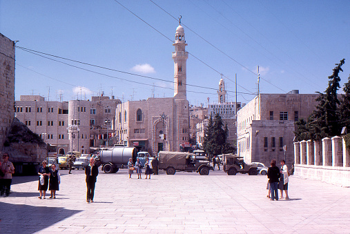 manger square outside the church central Bethlehem, Israel-Palestine April 12 1979 Tourists visiting with army trucks in background