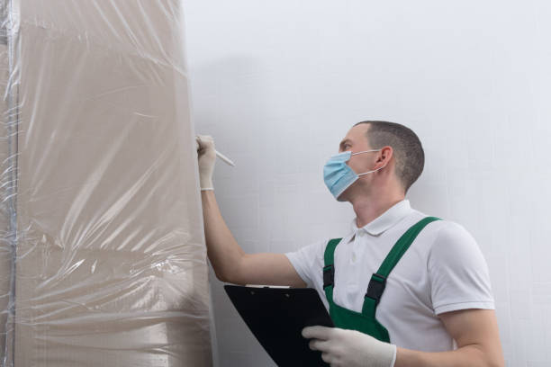 istock a man, wearing a protective mask, writes down the delivery address on a large cardboard box wrapped in polyethylene, there is a place for the inscription 1301042009