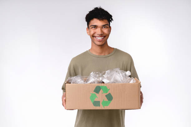 Adorable young african man holding a box with plastic bottles for recycling isolated over white background