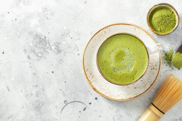 istock Matcha green tea latte in a cup with cream on a light concrete background. Top view with copy space 1301043074
