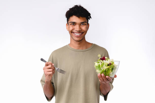 istock Handsome young african man eating salad with a fork isolated over white background 1301043347