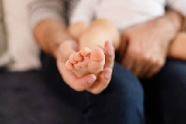 istock Father's hands carefully keeping baby's foot with tenderness 1301043464