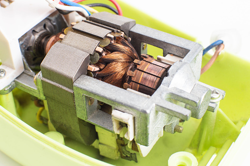 Broken electric motor in a household appliance hand mixer. Malfunction of the rotor and stator of electrical components, close-up, Engineering