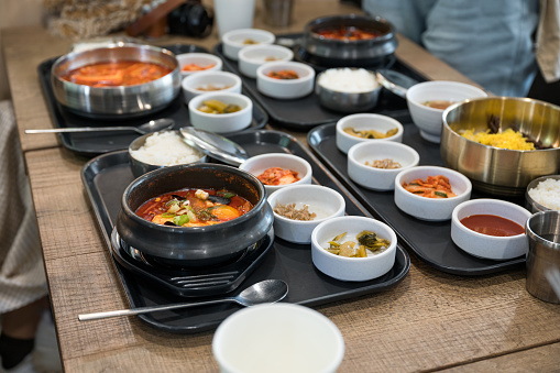 Various of Korean food with spicy soup, kimchi, noodles and vegetable pickle on tray in restaurant