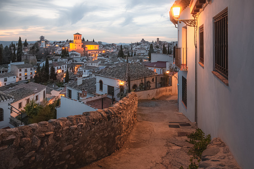 Old town sunset cityscape view of terracotta rooftops and the Church of San Salvador in the historic Moorish or Arab Quarter (albaicin) in Granada, Andalusia, Spain.