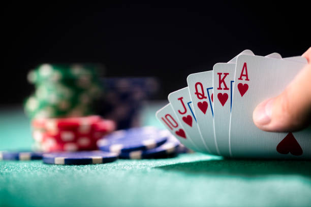 Playing poker in a casino holding winning royal flush hand of cards Playing poker in a casino holding winning royal flush hand of cards concept for gambling, betting and winning jackpot photos stock pictures, royalty-free photos & images