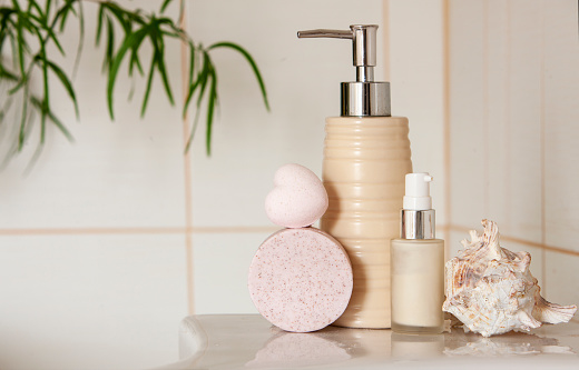 Bath ceramic bottle, soap, shell and bath bomb on Blurred bathroom interior background with sink