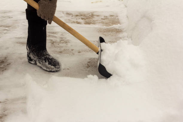 un uomo con gli stivali di feltro, con una pala tra le mani, rimuove la neve dal marciapiede dopo una nevicata. - snow remover foto e immagini stock