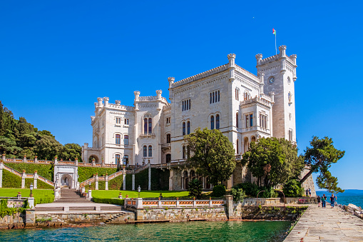 The Miramare Castle is a 19th-century castle facing directly on the Gulf of Trieste, with grounds that include an extensive cliff and a seashore park. Tourists visiting.