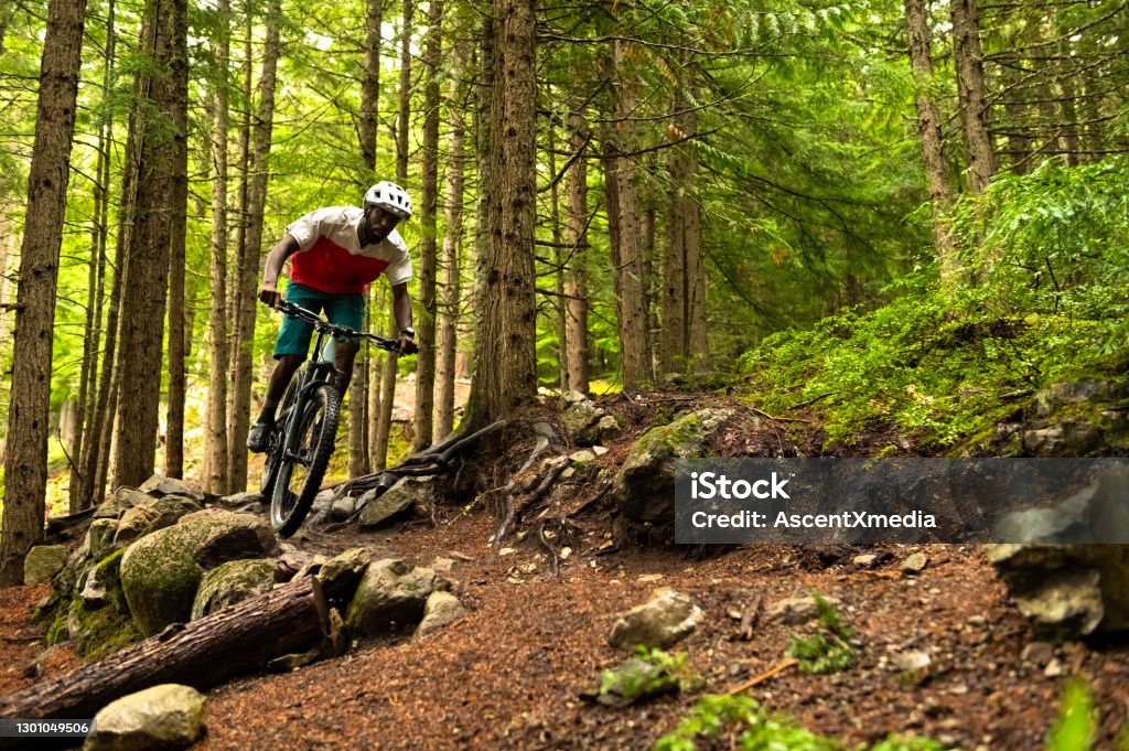 Male mountain biker riding in a forest African American athlete riding a mountain bike. Best biking destinations in North America. Living an active lifestyle. Mountain Biking Stock Photo